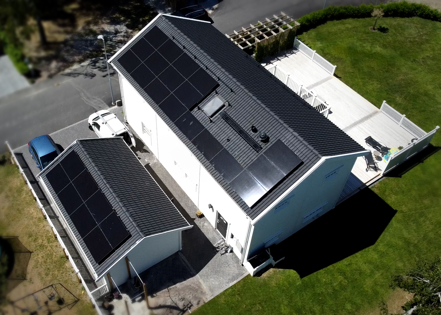 Solcellsanläggning med helsvarta solpaneler. Vit nybyggt hus med svart tak och svarta solceller.